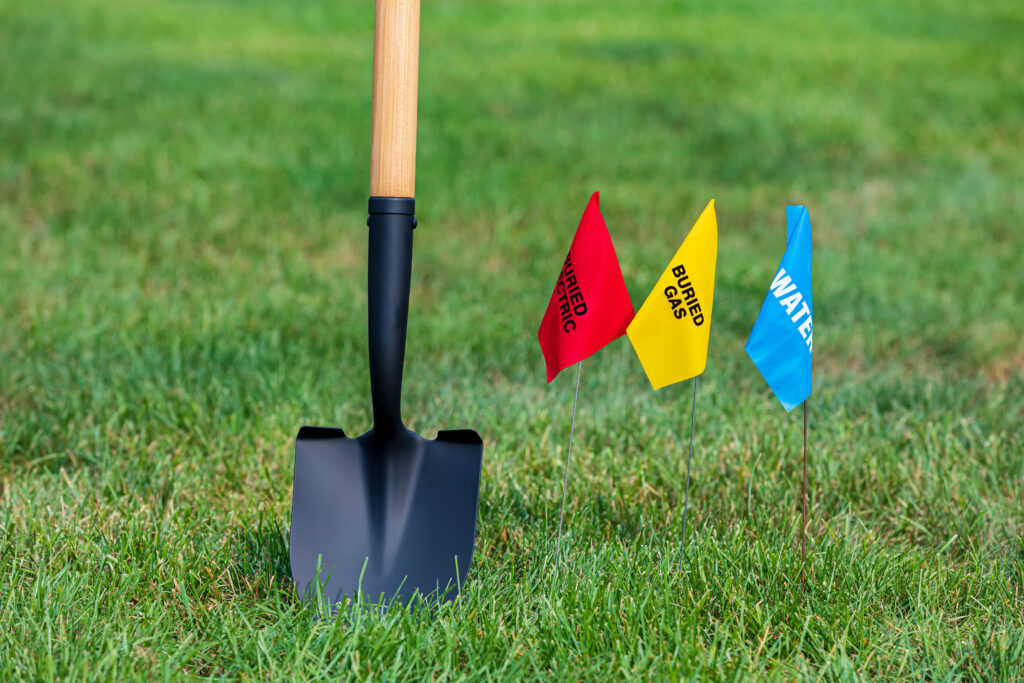 Shovel in grass next to utility location flags